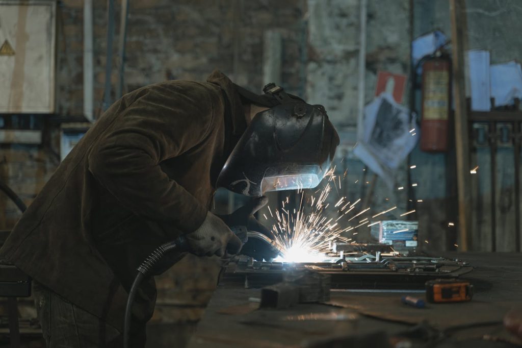 A skilled welder focused on welding a metal piece in an industrial workshop. Sparks flying vividly.